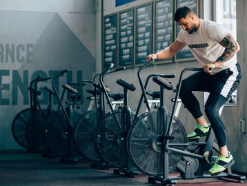 Man working out on an exercise bike in a gym.