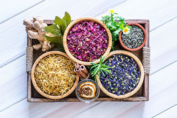 Tray with dried herbs and spices in wooden bowls.