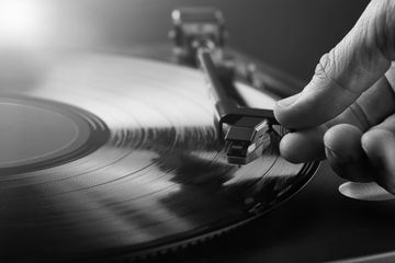 Hand placing the needle on a spinning vinyl record on a turntable.