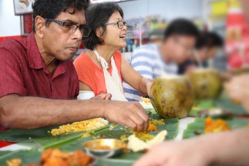 Family members dining in local Indian banana leaf rice restaurant. The benefits of banana leaf is not only serve as a plate but also it brings out flavour to a person's meal.