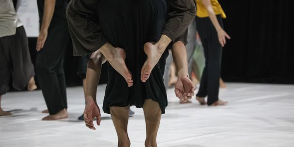 Dancers in an expressive pose with intertwined limbs during a modern dance performance.