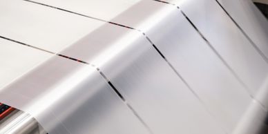 Thin, transparent plastic sheets being processed in a factory.