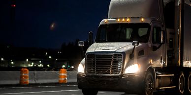 Semi-truck driving on highway at night.