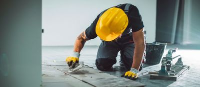 Professional flooring installer completing tile installation for a residential renovation project in