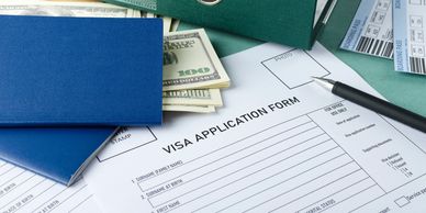 Visa application form with passports, cash, boarding passes, and a pen on a table.