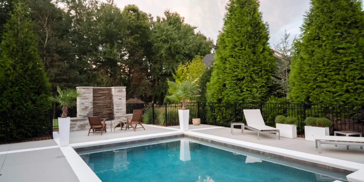 Modern backyard pool area with greenery and seating.