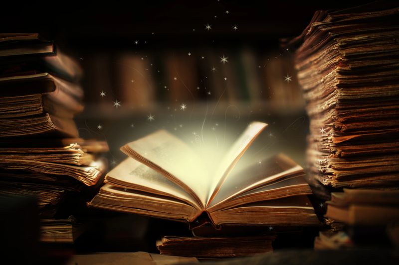 Magical book lying open on desk in library. Stars and shapes flying from glowing pages and illuminates surrounding.Fairy brush made from my own drawing.