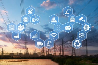 Industrial power lines with digital technology icons overlay at sunset.