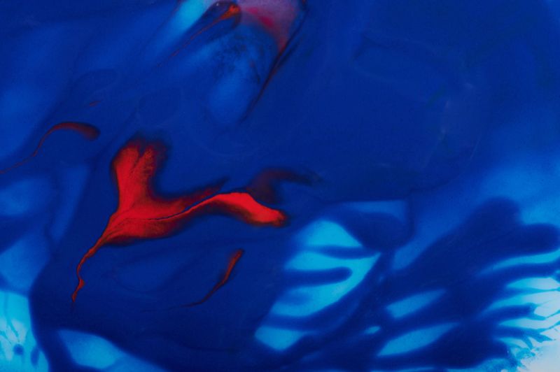 Blue paint pattern background with red swirls close up view