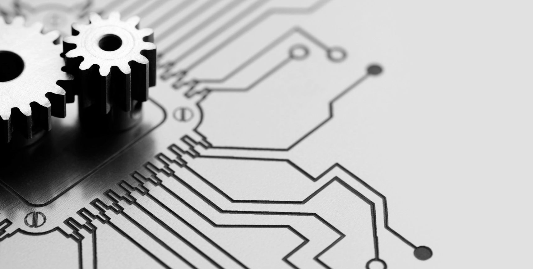 Two metal gears on a circuit board symbolizing technology integration.