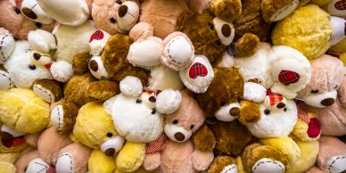 Pile of colorful teddy bears with red paw prints.