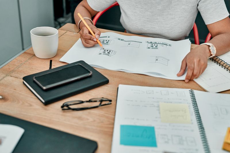 Closeup shot of an unrecognisable architect working with blueprints in an office