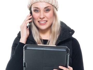 Woman smiling while talking on the phone and holding a tablet.
