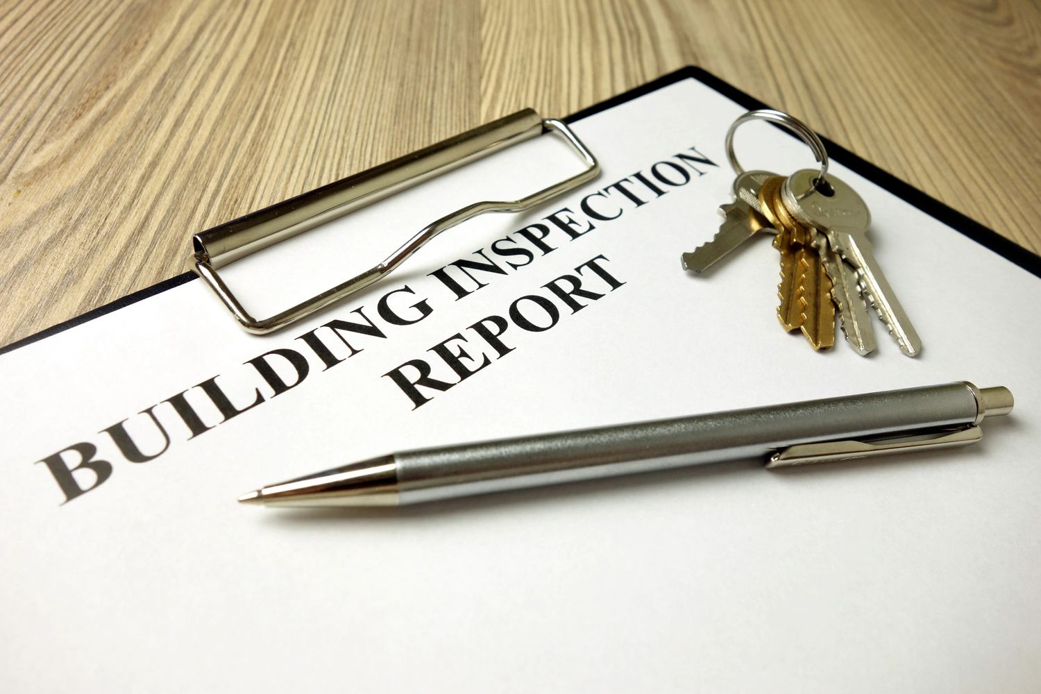 Building inspection report with pen and keys on wooden table.