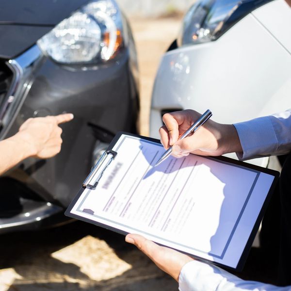 Person filling out accident report after minor car collision.