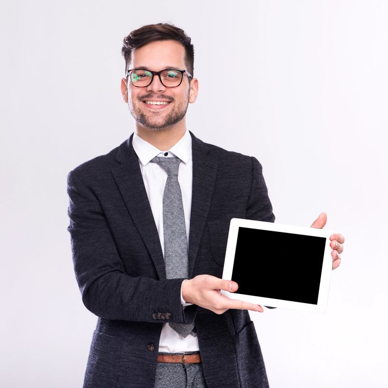Young handsome male businessman standing in studio and looking at digital tablet computer