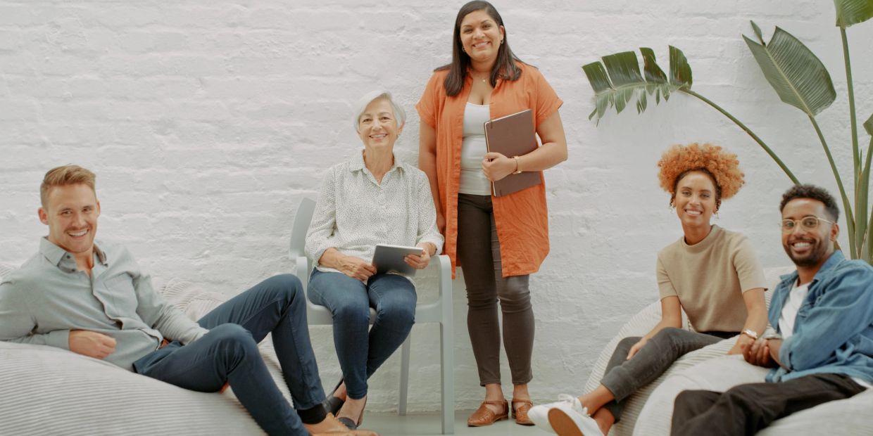 Group of five diverse people smiling indoors.