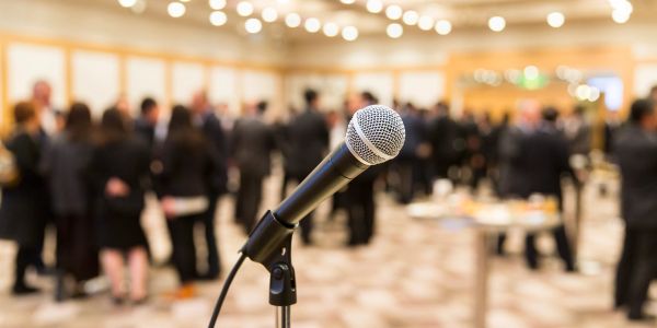 Microphone at an event with attendees in the background.