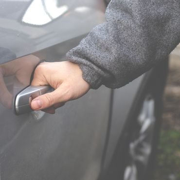 Hand gripping a car door handle to open the door.