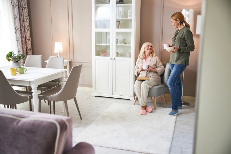 Happy adult lady resting with coffee while looking at volunteer in living room stock photo