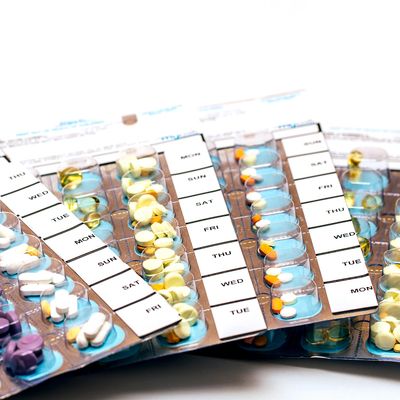 Weekly pill organizer filled with various medications for daily use.