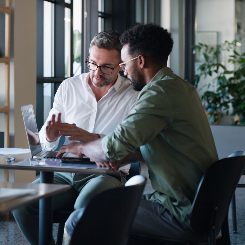 Shot of two businessmen using a laptop and having a discussion in a modern office