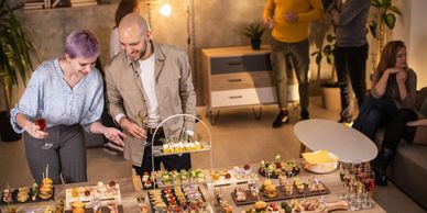 People enjoying a party with assorted appetizers and drinks on a table.
