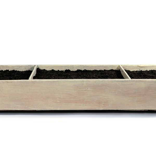 Wooden planter box divided into three sections filled with soil.