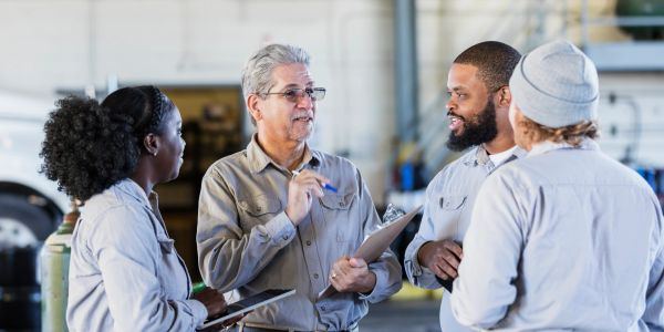 A person holding a wrench in an automobile garage.
