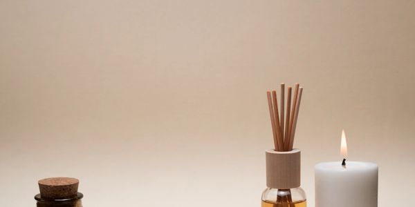 Aromatherapy setup with candles, diffuser sticks, and decorative elements on a beige background.