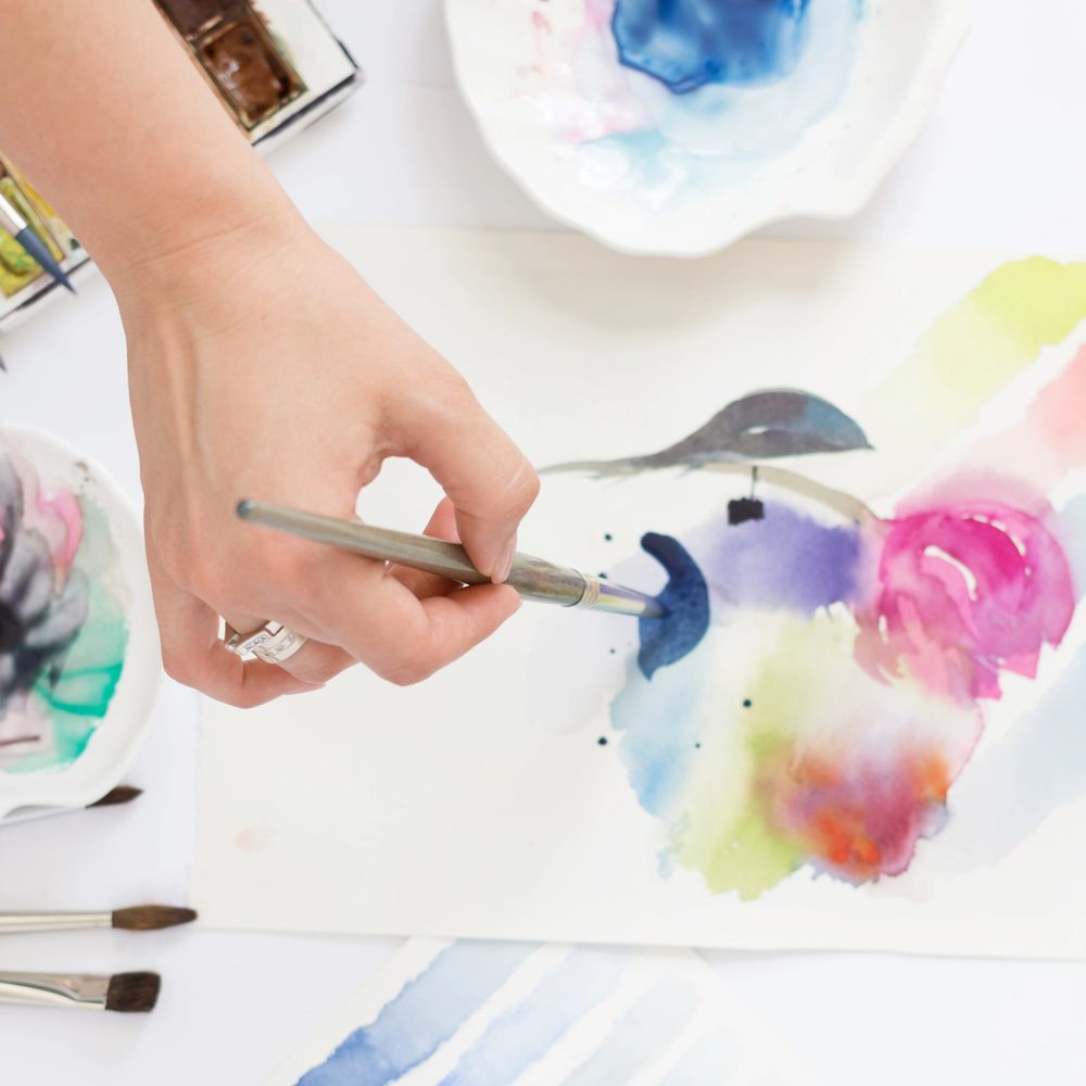 Hand painting vibrant watercolor artwork with brush and palette.