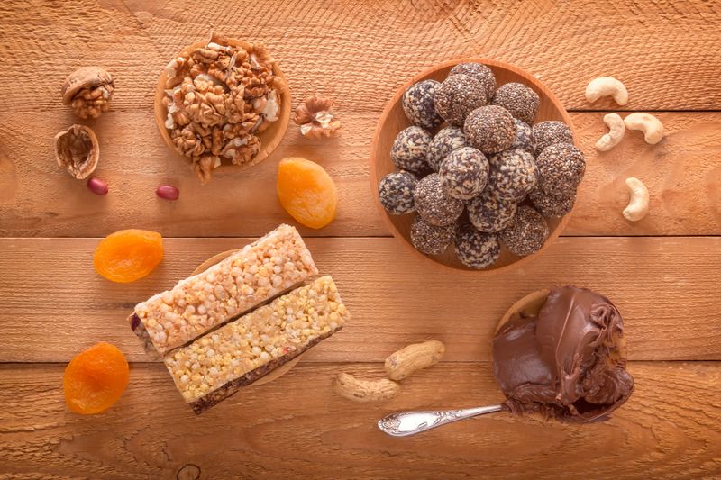Natural healthy raw energy bites, chocolate paste and mix of dried fruits with nuts on a dark table. Top view
