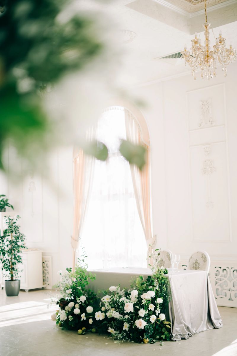 floral arrangement of white delicate flowers and fresh greenery in the design of the wedding table of the bride and groom