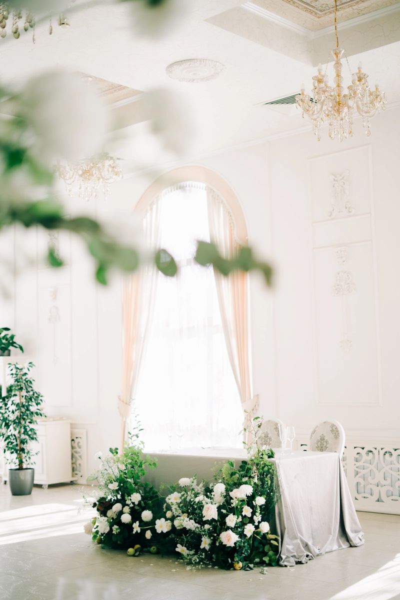 floral arrangement of white delicate flowers and fresh greenery in the design of the wedding table of the bride and groom