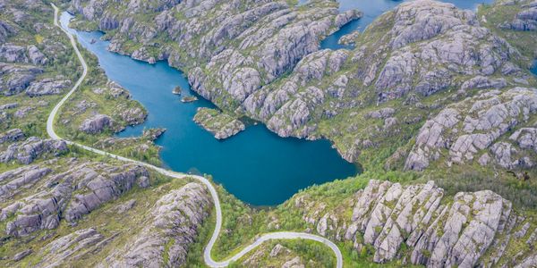 Winding road through rocky hills and blue lakes in a scenic landscape.