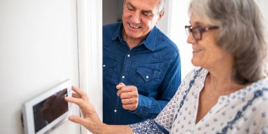 Senior couple adjusting a thermostat.