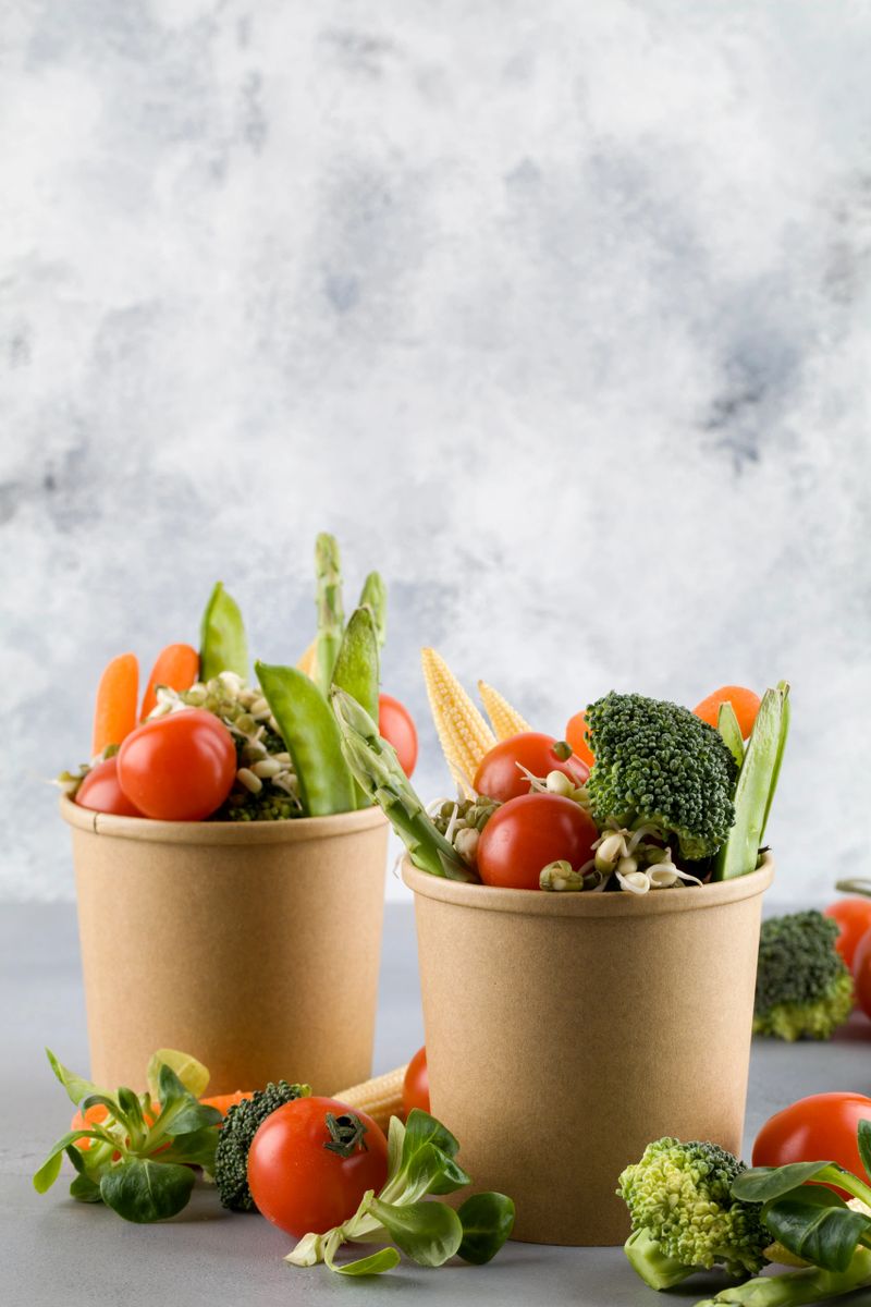 Healthy food in disposable eco friendly food packaging. Vegetables in the brown paper food containers on blue background. copy space