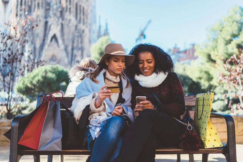 Young women in the city park making an online reservation with credit card