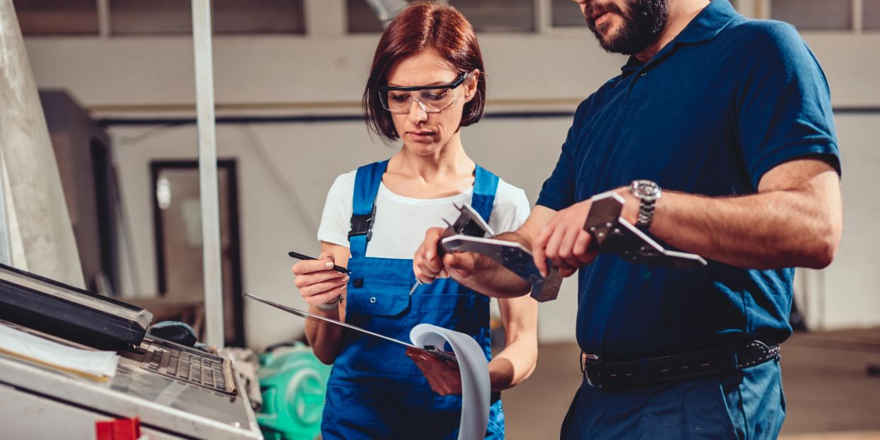 Two engineers inspecting measurements in a workshop.