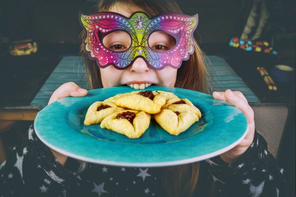 Girl with butterfly mask holding a plate of cookies.