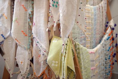Handwoven textiles with colorful patterns hanging on display.