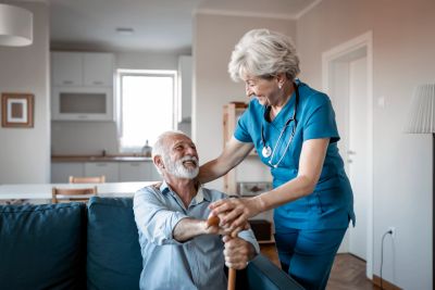 Nurse warmly assisting elderly man at home.