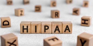 Wooden blocks spelling out HIPAA on a textured surface.