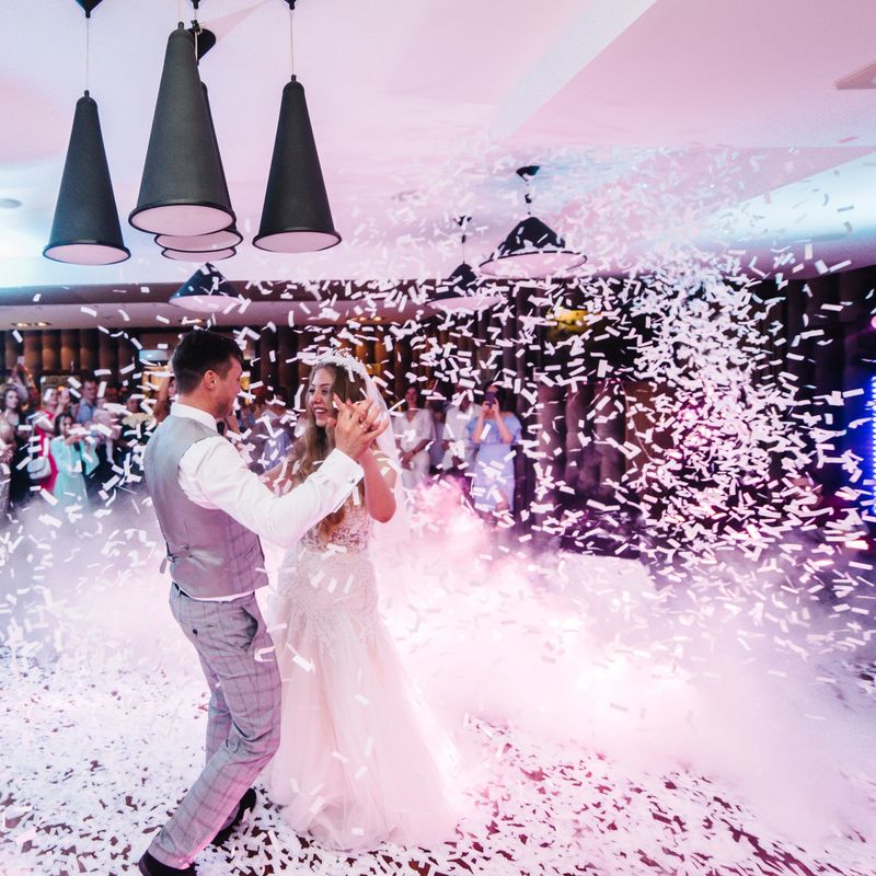First wedding dance of newlywed. Happy bride and groom dancing under confetti in the elegant restaurant with a wonderful light and atmosphere. Romantic moments.
