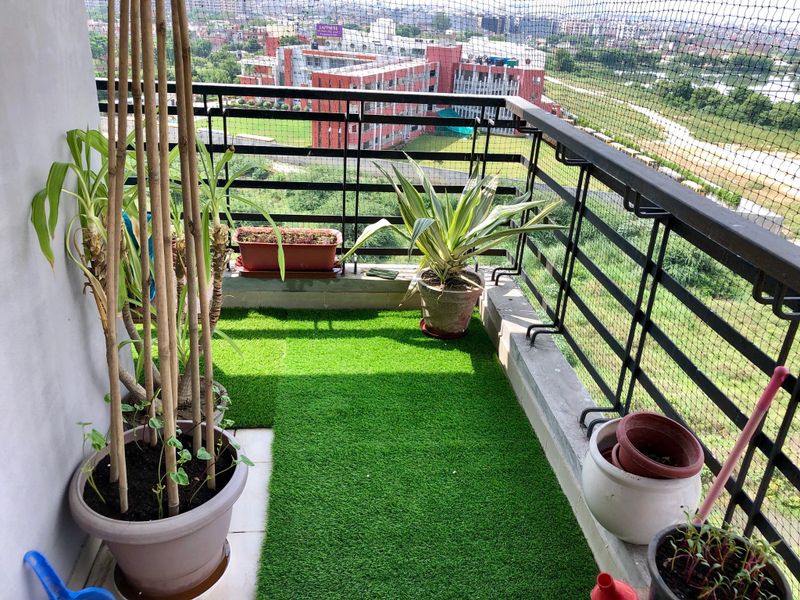 Stock photo of apartment balcony in Ghaziabad, India decorated with potted plants and artificial green grass turf. Gardening and exterior design concept.