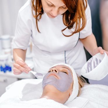 A woman applying a facial mask to a client in a spa.