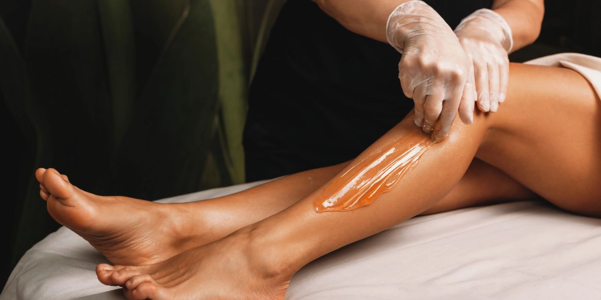 Applying wax on a woman's leg for hair removal.