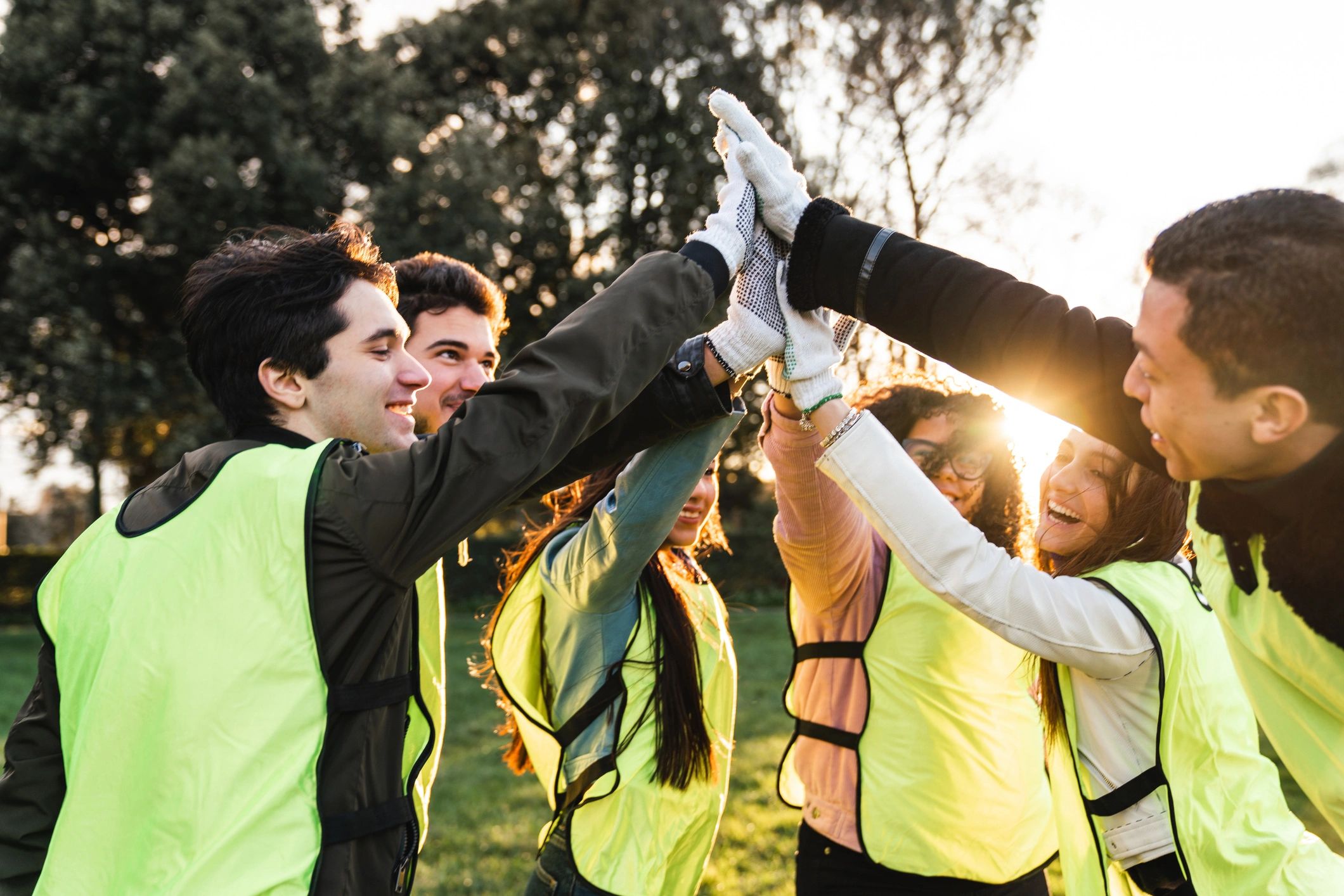 Group of people giving a group high-five outdoors.