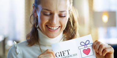 Smiling woman holding a $100 gift certificate with a heart design.