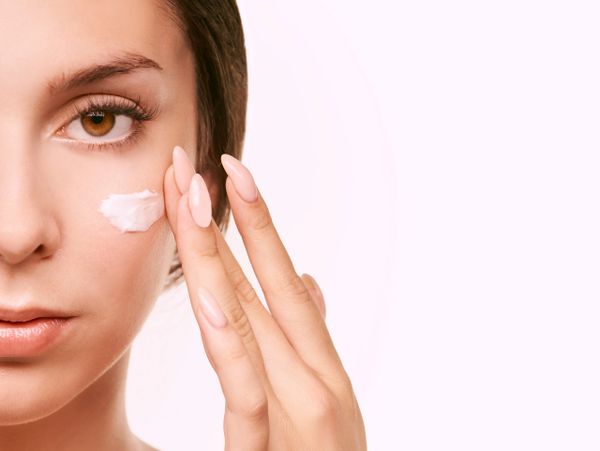 Woman applying cream to her face for skincare.